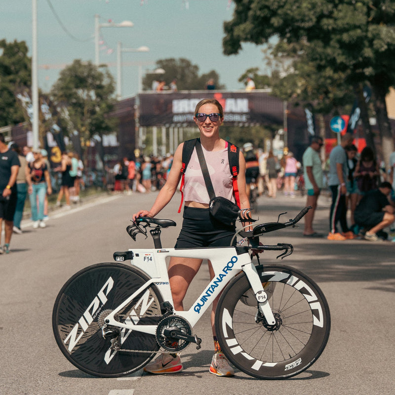 Person on a bicycle in a race setting with spectators and event branding.