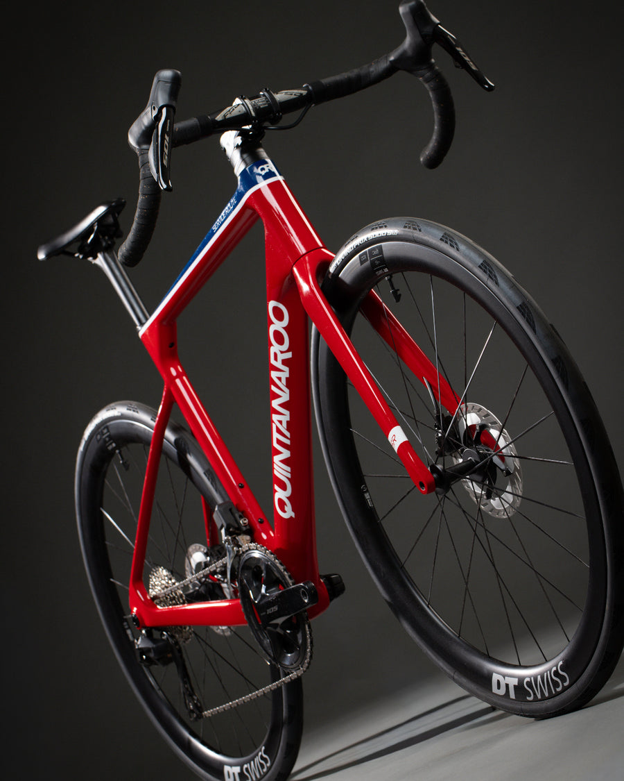 A custom Service Route road bicycle with black components, drop handlebars, and black wheels, photographed on a dark gray studio background.