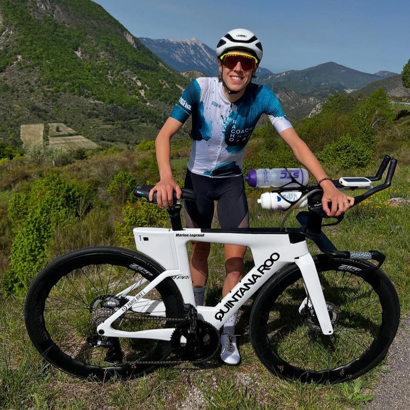 Cyclist with a white bicycle in a mountainous landscape