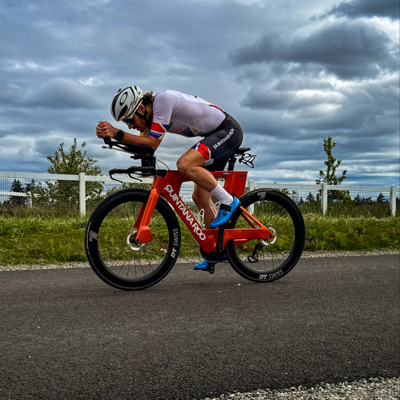 Cyclist riding a red bicycle on a road with a cloudy sky