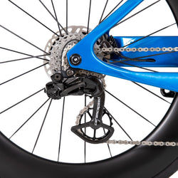 A closeup image of the wheel/chain of a blue QR bicycle on a white background.