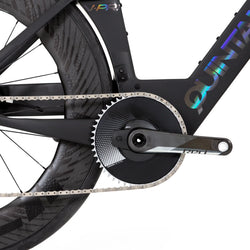 A closeup of the pedal/wheel of a black QR bike with iridescent logo lettering on a white background